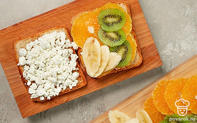 Завершите приготовление тостов. Нанесите на тосты творог ровным, достаточно толстым слоем. Нарежьте тонкими дольками киви, банан и очищенный от цедры апельсин. Выложите их на тосты.