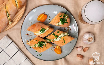 Перед подачей порежьте багет с чесночным соусом на несколько частей, выложите их на тарелку и украсьте листьями петрушки.