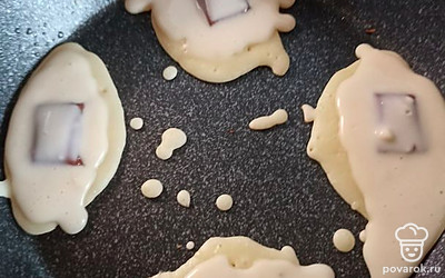 Выкладываем на сковородку часть теста. Кладем по одной дольке шоколада и заливаем вторым слоем теста. Обжариваем с двух сторон.