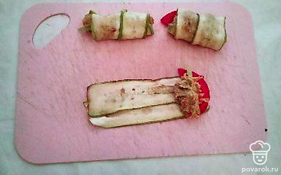 Болгарский перец и помидоры нарежьте на небольшие полосочки. Две полоски кабачка поставьте на стол, выложите на них полоску перца и помидора, сверху добавьте измельченную начинку. Заверните рулетик и поставьте на тарелку. Проделайте то же самое со всеми ломтиками кабачков.