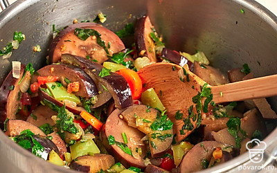 Приготовьте аджапсандал. В кастрюлю с толстым дном выложите баклажаны, лук с морковью, болгарский и стручковый перец, нарезанные базилик с петрушкой и тертые помидоры. Все хорошо перемешайте и тушите овощи на медленном огне 15 минут. Затем добавьте в овощи приправу уцхо-сунели, черный молотый перец и пасту из кинзы и соли. Аджапсандал хорошо перемешайте и снимите с огня.