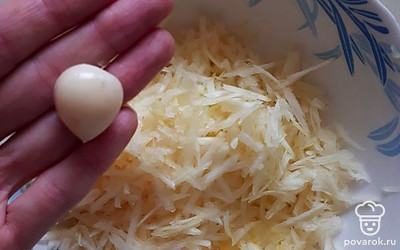 Возьмите глубокую тарелку. Натрите кабачок на крупной терке, а чеснок — на мелкой.