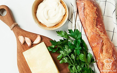 Чеснок очистите и пропустите через пресс. Сыр натрите на крупной терке. Петрушку переберите, промойте, просушите и мелко нарежьте, оставив листочки с одной веточки для украшения. Помидоры помойте и удалите плодоножку, затем нарежьте дольками. Приготовьте противень, пергамент и кондитерский мешок.