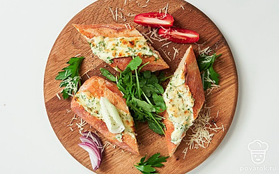 Багет с майонезом разрежьте на три части и выложите их на круглую доску. Украсьте кусочки багета листиками петрушки, а рядом положите дольки помидоров.