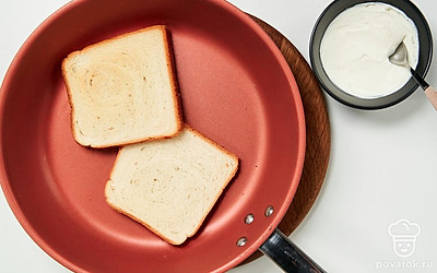 Начните готовить тост. Хлеб подсушите на сухой сковороде или в тостере. Смажьте творожным сыром.