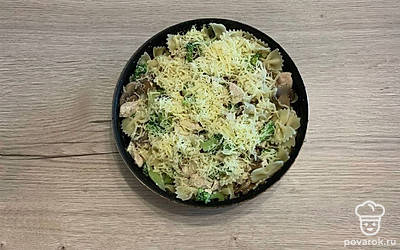 Выложите курицу в сковороду с грибами и брокколи. Добавьте мелко нарезанный чеснок. Аккуратно перемешайте, добавьте соль. Сюда же добавьте отваренные макароны и посыпьте сверху натертым сыром, быстро перемешайте.