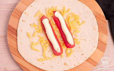 Выложите на тортилью сыр, сосиски и майонез.