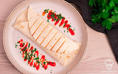 Выложите тортилью на порционную тарелку и украсьте кетчупом или любым соусом и свежей зеленью.