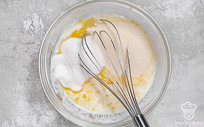 Влейте в миску кефир. Добавьте сахар и сухие дрожжи. Хорошо перемешайте, чтобы все крупицы растворились.