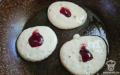 Порционно выложите тесто на сковороду. В середину на каждый оладушек положите ягоды клубники. 