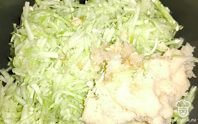 Отожмите воду из кабачка и картофеля. Сложите в глубокую емкость. Зубчики чеснока почистите и пропустите через пресс. Добавьте к овощам.