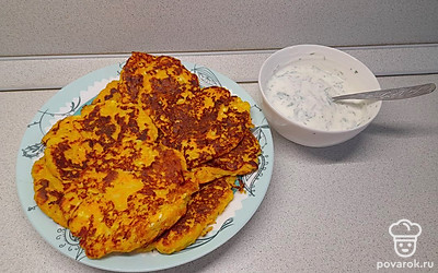 Подавайте морковно-кабачковые оладьи теплыми с соусом из йогурта и свежей зелени.