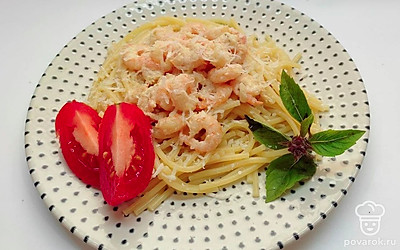 Подавайте креветки с пастой, разложив в порционные тарелки. Посыпьте блюдо тертым пармезаном, дополните ломтиками свежего томата и веточкой базилика.