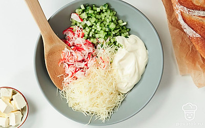 Приготовьте начинку. Огурцы смешайте в миске с крабовыми палочками, добавьте тертый сыр. Посолите и добавьте 3 ст. л. майонеза. Перемешайте начинку.