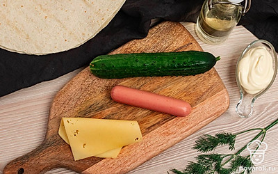 Приготовьте необходимые ингредиенты. Огурец и зелень помойте. Сосиску очистите от обертки.