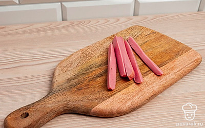 Сосиски порежьте на четыре части, так чтобы получились длинные полоски.