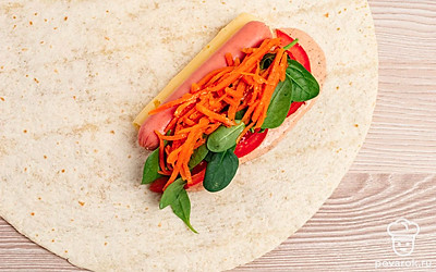 Сверху на помидоры и сосиску положите зелень и корейскую морковь