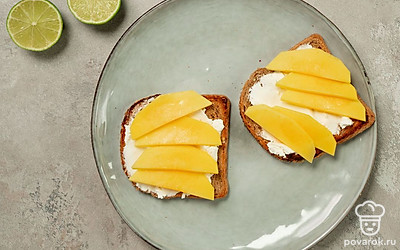 Соберите тосты. На обжаренный хлеб намажьте рикотту и аккуратно выложите дольки манго. Сбрызните фрукт соком лайма, выжатым из дольки цитрусового.