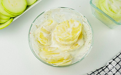 Картофель помойте, просушите бумажным полотенцем, очистите и нарежьте на тонкие кружочки. Затем приготовьте соус для картофеля: в миске смешайте сметану, соль, перец и укроп. Выложите в соус картофель.