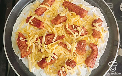 Готовую тортилью смажьте сливочным сыром, посыпьте тертым твердым сырым. Сверху него положите мясо, на него – снова твердый сыр. Тортилью с начинкой положите на разогретую сухую сковороду и накройте другой лепешкой. Жарьте по 1 минуте с обеих сторон.