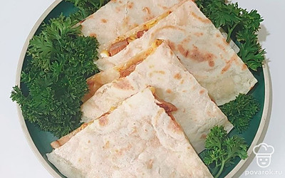 Готовую кесадилью украсьте зеленью, в том числе листьями салата. Положите свежие помидоры или нарезку болгарского перца. Подайте соус.