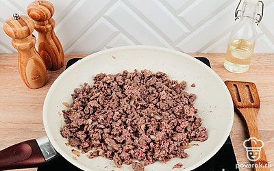 Пока кабачки готовятся, лук нарежьте кубиками. Разогрейте другую сковороду с растительным маслом. Обжарьте лук 2-3 минуты до золотистого цвета. После чего добавьте к нему фарш и обжарьте все вместе.