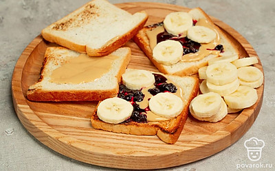 Приготовьте тосты. На обжаренный хлеб намажьте тонким слоем джем из черники, затем пасту, выложите аккуратно кружочки банана. Второй кусочек хлеба также смажьте джемом и пастой, положите сверху, слегка прижмите. Разрежьте готовый тост на треугольники.