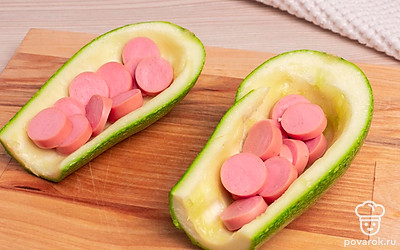 Выложите нарезанные сосиски в кабачки.