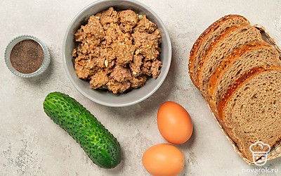 Хлеб нарежьте на треугольники. Яйца сварите вкрутую, очистите от скорлупы. Одно яйцо натрите на терке, второе разрежьте пополам, достаньте желток и натрите на терке. Огурец вымойте, очистите от кожуры и натрите на терке. Откройте баночку с говяжьей печенью. Укроп и петрушку для подачи вымойте, обсушите на бумажных полотенцах.