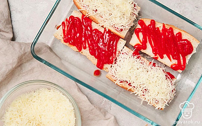 Приготовьте багет с кетчупом. Каждую половинку багета смажьте кетчупом. Сверху посыпьте сыром. Готовьте в духовке при 180 градусах 4-5 минут либо в микроволновой печи на максимальной температуре 1-2 минуты.