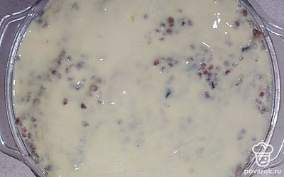 Соедините грибы с гречкой, перемешайте. Выложите гречку с грибами поверх овощей. Яйца разбейте в глубокую емкость и разболтайте вилкой. К яйцам добавьте сметану. Чеснок очистите, пропустите через пресс и также добавьте в емкость. Перемешайте заливку.