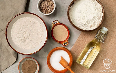 Подогрейте воду до температуры немногим выше человеческого тела. Просейте ржаную и пшеничную муку через мелкое сито. За 20 минут до выпекания включите духовку на 200 градусов, чтобы она нагрелась. Противень застелите листом пергаментной бумаги.