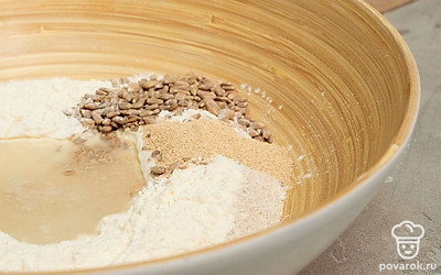 Сделайте тесто. Смешайте в большой миске ржаную и пшеничную муку, дрожжи, соль и перец. Влейте в сухую смесь теплую воду, еще раз хорошо перемешайте. Добавьте подсолнечное масло и семечки. Замесите тесто, после чего отложите его в теплое место на 1,5 часа. Когда тесто увеличится в объеме, помните его, после чего оставьте еще на 1 час.