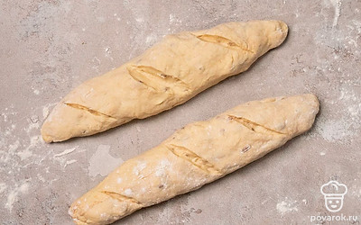 Сформируйте багеты. Рабочую поверхность присыпьте мукой. Выложите на нее готовое тесто, разделите его на 4 равные части. Каждую часть разомните и сформируйте из нее багет, слегка растягивая его по сторонам.