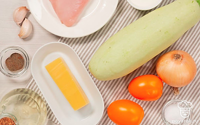 Подготовьте продукты для фаршированных кабачков в духовке. Кабачки вымойте, обрежьте хвостики и разрежьте вдоль, на две одинаковые половины. Из кабачков удалите мякоть. Мясное филе мелко нарежьте, мякоть кабачка измельчите, лук нарежьте четверть кольцами, помидоры — кубиками. Сыр натрите на крупной терке. Зелень мелко порубите. Чеснок почистите, пропустите через пресс. Совет: Для приготовления блюда выбирайте кабачки маленького или среднего размера. Удаляйте мякоть очень осторожно — важно оставить стенки овоща целыми.