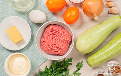 Подготовьте продукты для фаршированных кабачков. Укроп и петрушку помойте, мелко нарежьте. Почистите чеснок, пропустите через пресс один зубчик чеснока и отложите чесночную массу для соуса, остальные оставьте для фарша. С репчатого лука снимите шелуху, разрежьте на четыре части. Помидоры помойте, нарежьте мелкими кубиками. Кабачки помойте, нарежьте поперек, чтобы получились равные по высоте бочонки. Мякоть удалите, оставив дно. Сыр натрите на средней терке. Совет: Кориандр можно заменить базиликом, кинзой, смесью прованских трав.