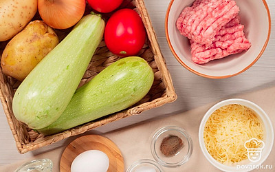 Подготовьте продукты для фаршированных кабачков в духовке. Кабачки разрежьте вдоль на две половины. Извлеките ложкой мякоть, натрите ее на мелкой терке. Луковицу измельчите. Помидоры нарежьте дольками. Картофель почистите, натрите на средней терке. Совет: Кабачки можно приготовить и в виде бочонков, если разрезать их поперек, оставив дно из мякоти и выскоблив основную часть сердцевины.