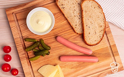 Приготовьте необходимые ингредиенты. Сосиски очистите, корнишоны достаньте из рассола, помидоры помойте.