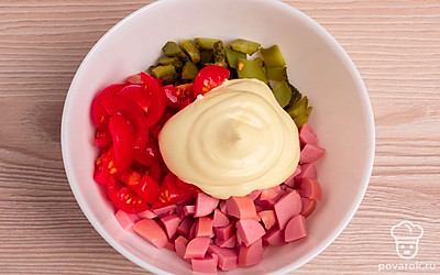 В чашу добавьте порезанные овощи и сосиски, добавьте майонез и все тщательно перемешайте.