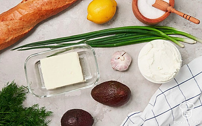 Подготовьте продукты для приготовления багета с авокадо. Багет нарежьте средними ломтиками. Сливочное масло растопите. Извлеките из авокадо мякоть, нарежьте тонкими ломтиками. Чеснок почистите, пропустите через пресс. Зелень измельчите. Совет: Сливочный сыр можно заменить на творожный.