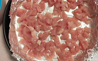 Порезать мелкими кусочками куриное филе. Выложить его первым слоем в предварительно смазанную форму для запекания. 