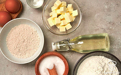 Просейте два вида муки, чтобы избежать попадания в тесто комочков. Сливочное масло заранее достаньте из холодильника, чтобы оно стало мягким. Подготовьте пищевую пленку и деревянную лопатку, чтобы перемешивать ингредиенты. Смажьте форму для выпечки растительным маслом или застелите специальной бумагой.