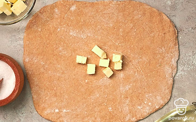 Приготовьте тесто. В холодной воде размешайте яйца, соль и уксус. В отдельную миску добавьте два вида муки, залейте их яичной смесью. Замесите тесто, заверните его в пищевую пленку и оставьте на 20 минут при комнатной температуре. Затем раскатайте полученное тесто в прямоугольник толщиной 0,5 см, в середину выложите размягченное сливочное масло, еще раз накройте тесто пленкой, после чего раскатайте масло по всей поверхности теста.