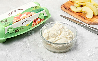 Приготовьте творожную основу. В чаше блендера соедините творог «Станция молочная», манную крупу «Селяночка», яйца «Селяночка», сахар «Экстра» и ванилин. Смешайте продукты в течение 5–7 минут до однородности. Переложите основу в форму, добавьте дольки яблок, аккуратно перемешайте.