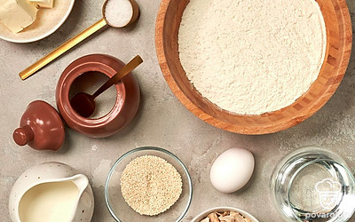 Муку просейте в миску. Воду подогрейте до 40 градусов. Сливки достаньте из холодильника, чтобы они нагрелись до комнатной температуры. Сливочное масло растопите. Яйцо обработайте 3%-ным раствором соды и ополосните. Разломите прессованые дрожжи, положите их в миску, залейте 0,5 стакана воды и добавьте 1 ч. л. сахара. Оставьте на 10 минут в теплом месте. Застелите противень для выпечки пергаментом.