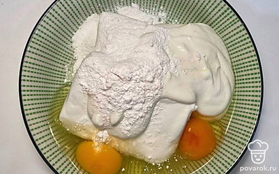 Поместите творог в емкость и немного разомните его. Далее добавьте яйца, рисовую муку и сладкий йогурт. Все тщательно перемешайте.