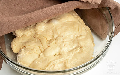 Замесите тесто. В миску засыпьте муку, добавьте к ней дрожжи, соль и сахар, перемешайте. Добавьте в смесь подсолнечное масло, затем постепенно влейте теплую воду, замешивая тесто сначала ложкой, а затем руками. Когда тесто будет готово, сформируйте из него шар, положите в миску, накройте полотенцем и оставьте на 1 час.