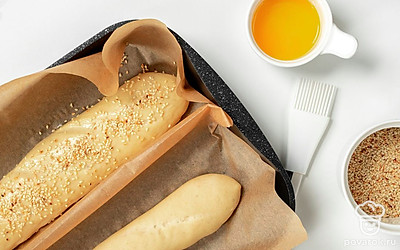 Поставьте багет выпекаться. Слегка взбейте яичный желток и смажьте им поверхность багета. Извлеките полотенца, посыпьте тесто кунжутом и поставьте его в духовку на 20-30 минут.