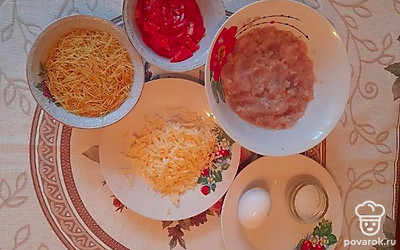 Натрите сыр на крупной терке, помидор нарежьте небольшими кусочками, лук прокрутите через мясорубку и добавьте его к фаршу. Поперчите и посолите фарш.