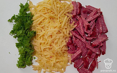 Измельчите свежую зелень, добавьте порезанную колбасу и сыр. После того как тесто отдохнуло, разделите его на несколько шариков и раскатайте в тоненький пласт